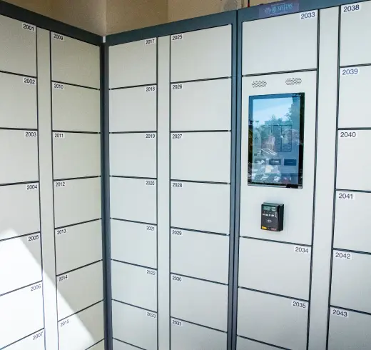 A modern parcel locker system with multiple numbered compartments and an electronic screen for access.